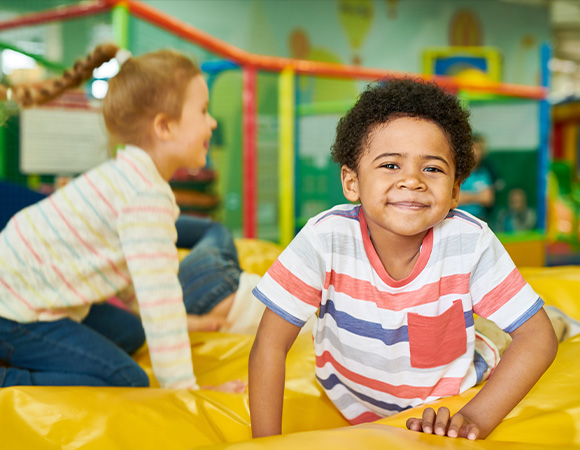 happy children playing in indoor play area on soft yellow bounce surface engaging in fun activities